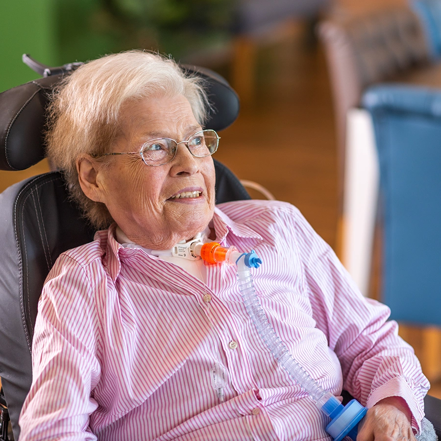Klientin im Raum auf einem Stuhl sitzend lächelt in die Ferne.